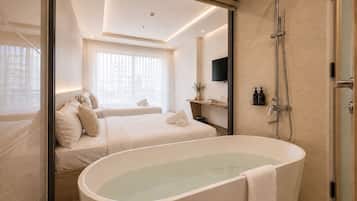 A modern bathroom with a freestanding bathtub, a shower, and a bed with a view of the city.