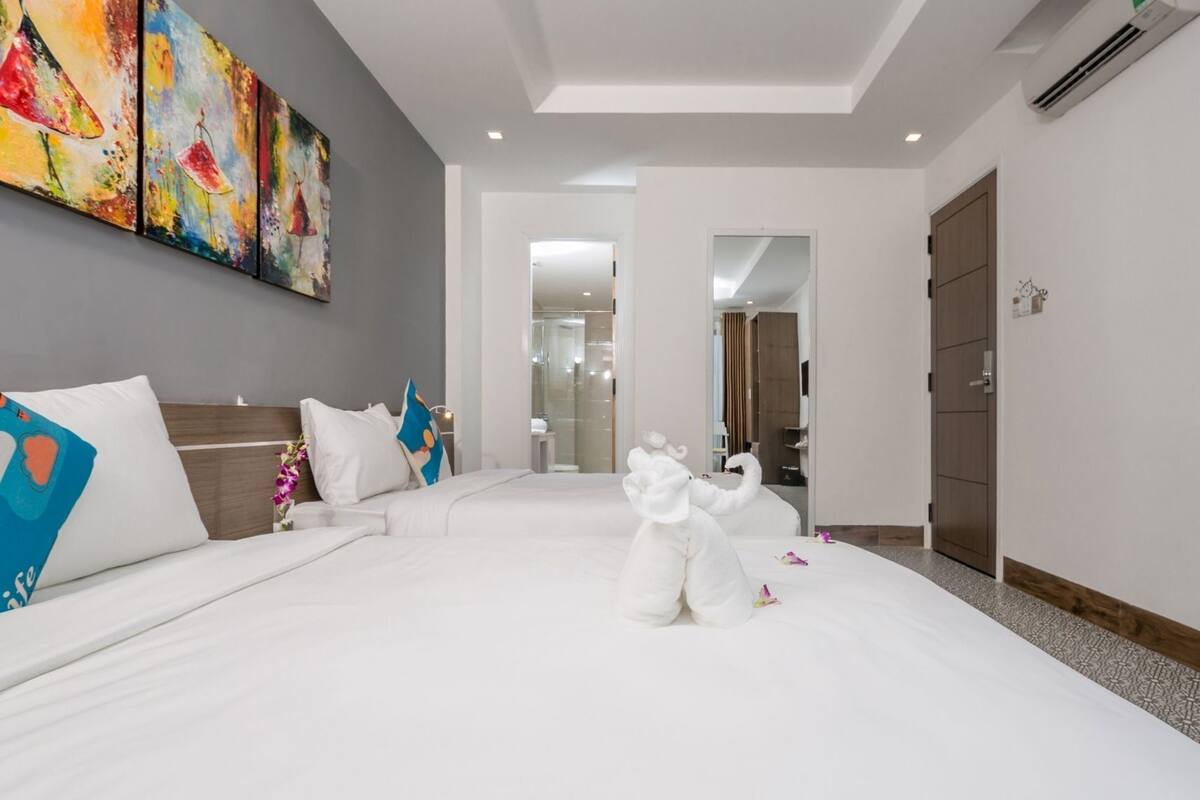 Ein Hotelzimmer mit einem großen Bett, einem Sofa, einem Bild an der Wand und einem durchgegangenen Tür erkennbaren Badezimmer.