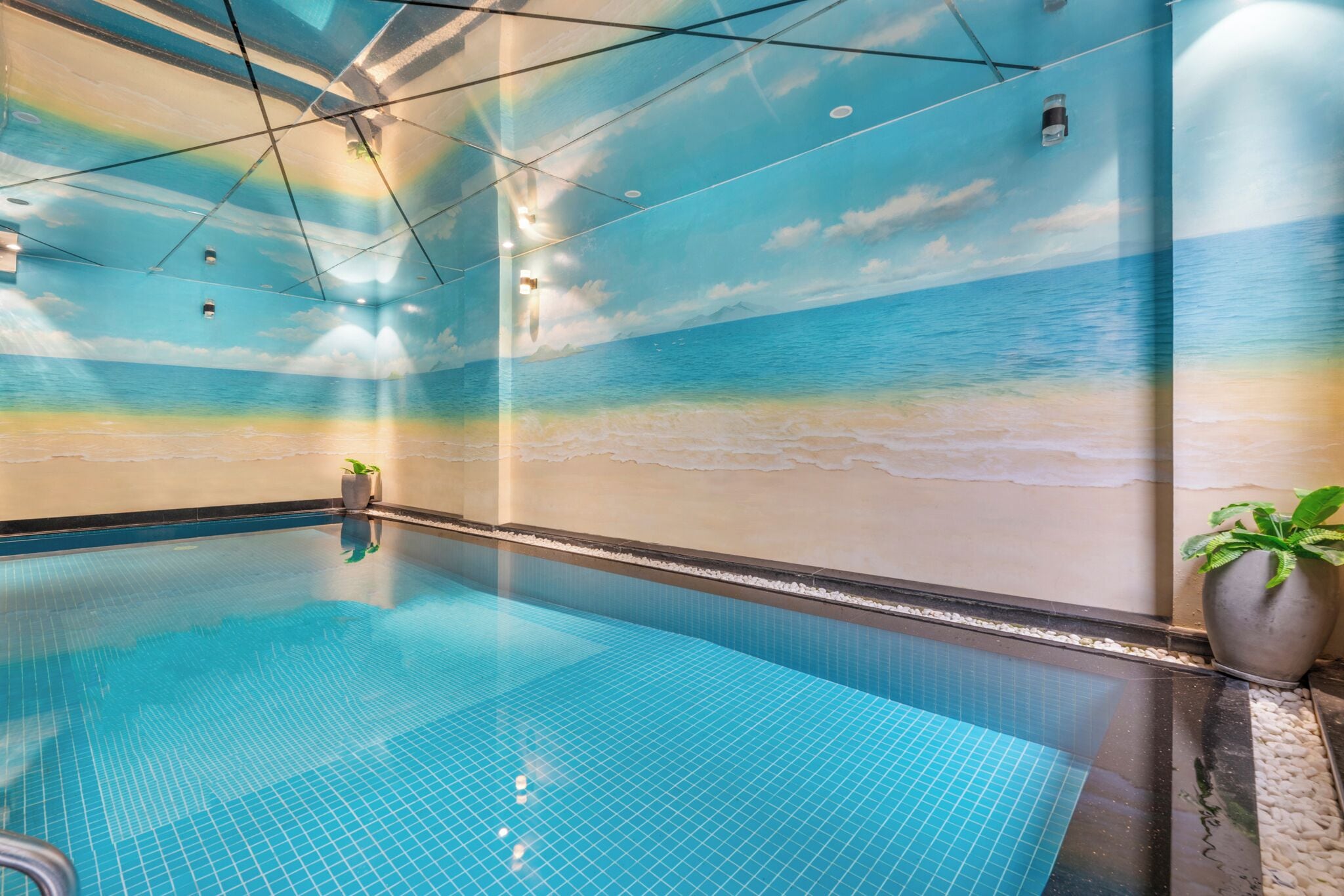 Una piscina interior con un mural que representa una playa en las paredes.