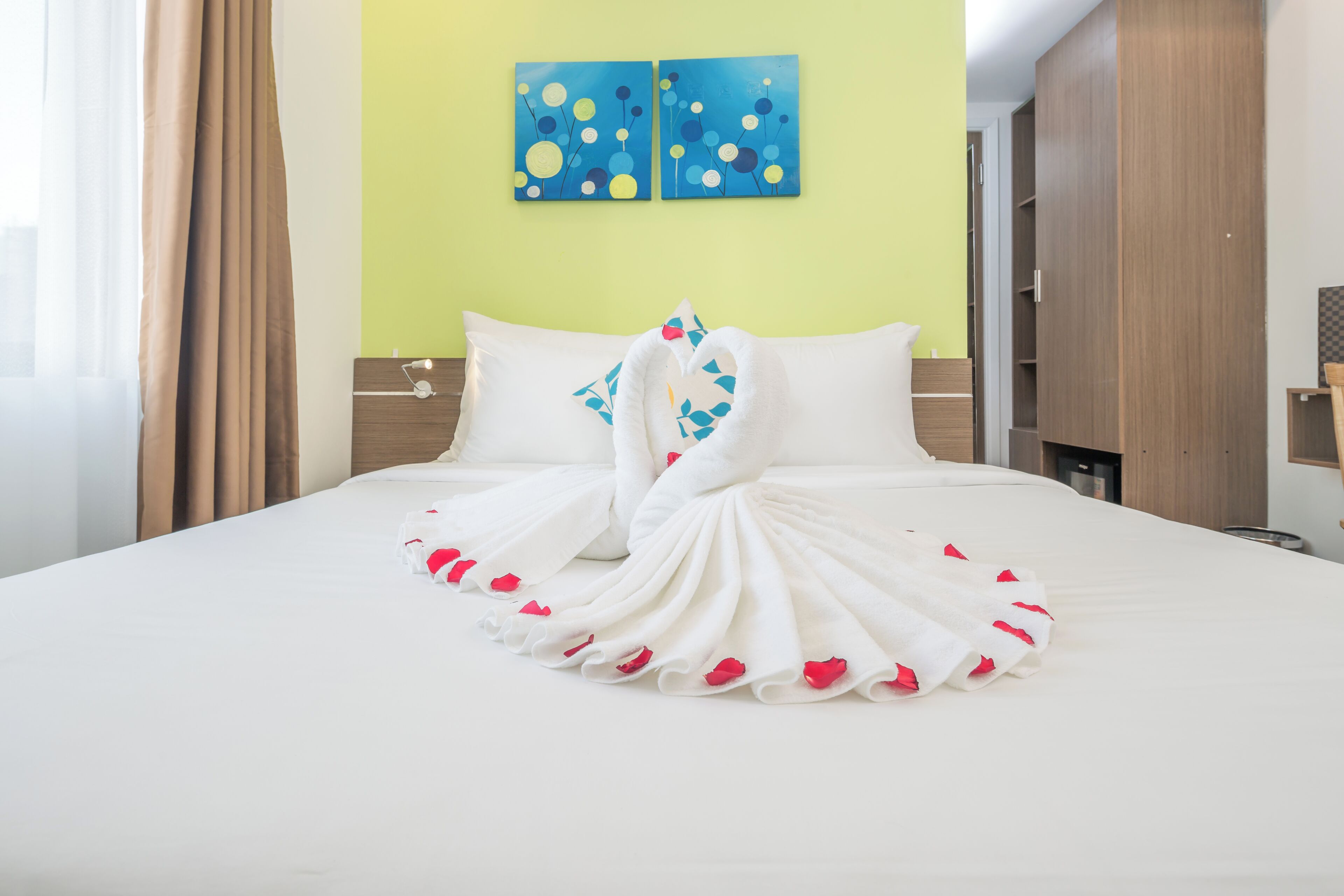 A hotel room with a neatly made bed, a nightstand, a lamp, and a wardrobe.