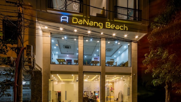 Un hôtel appelé Da Nang Beach, avec une façade moderne, de grandes fenêtres et un vélo garé à l’extérieur.
