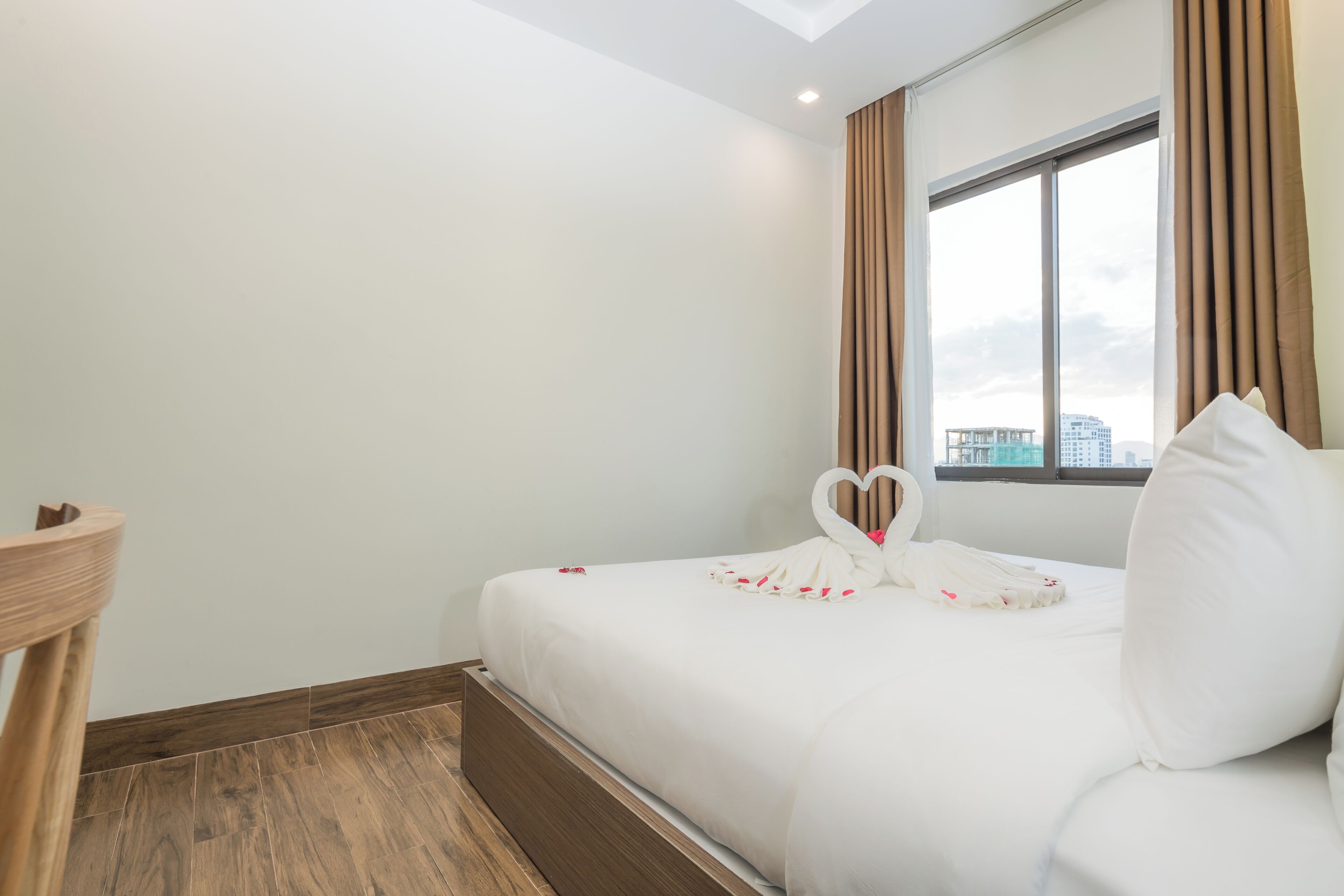 Una habitación de hotel con una cama, una mesita de madera y una ventana con cortinas.