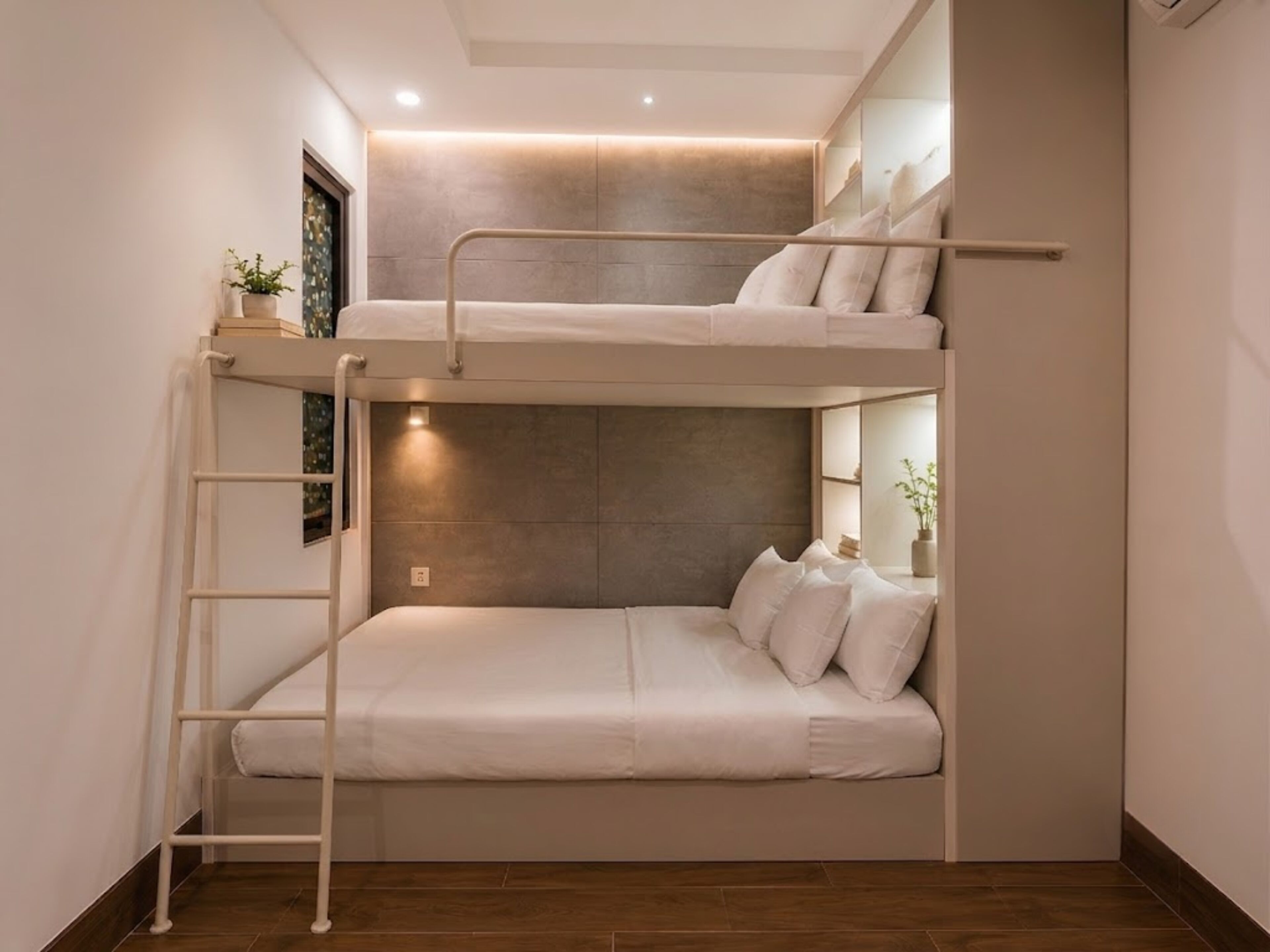 Un lit superposé avec une échelle, une table de chevet avec une plante et une étagère fixée au mur.