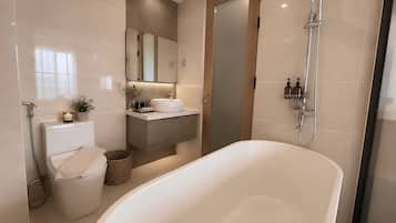 Ein modernes Badezimmer mit freistehender Badewanne, Toilette, Waschbecken mit Spiegel darüber und einer Duschkabine.