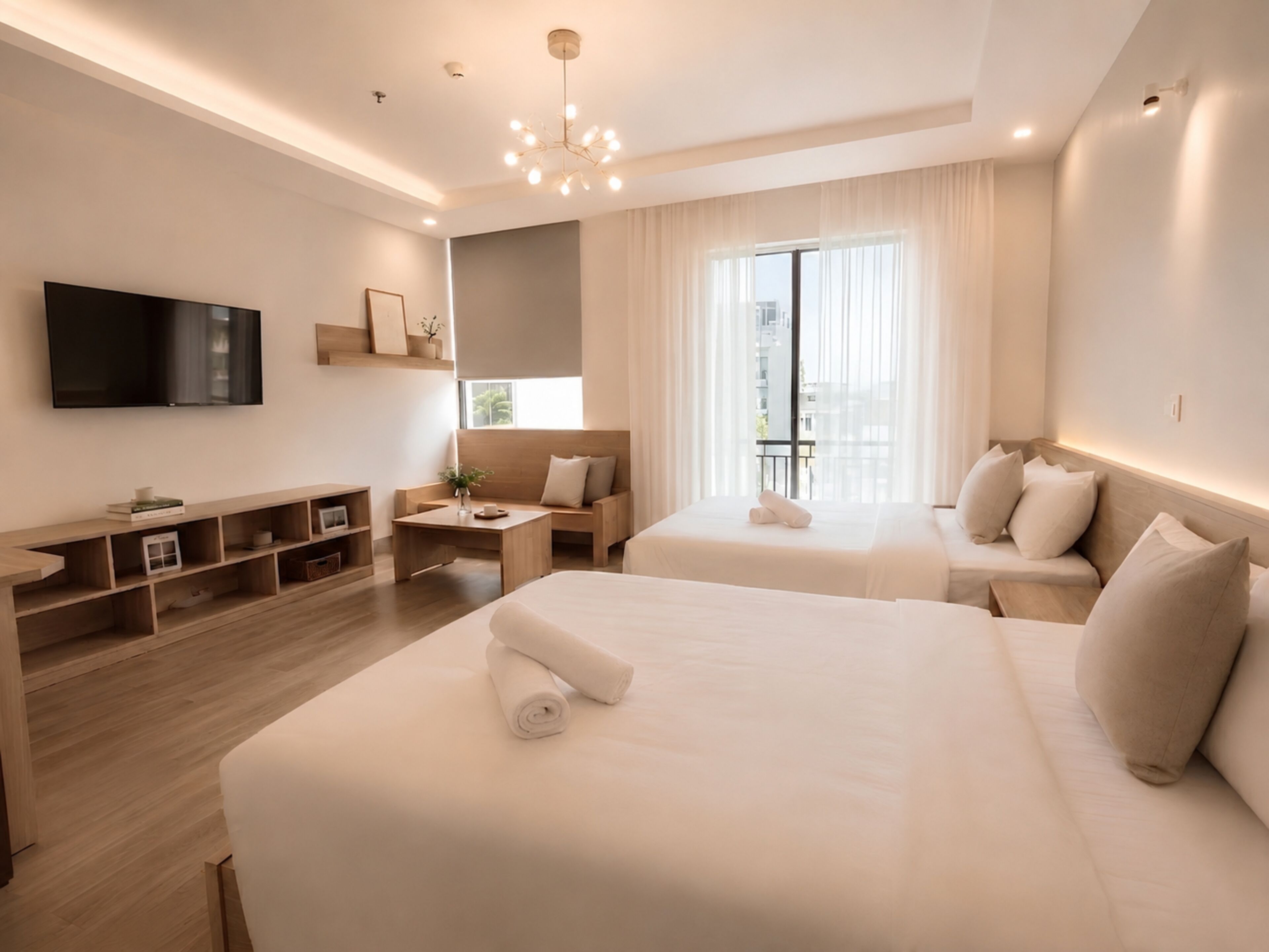 A hotel room with a bed, a sofa, a TV, a desk, and a window with curtains.