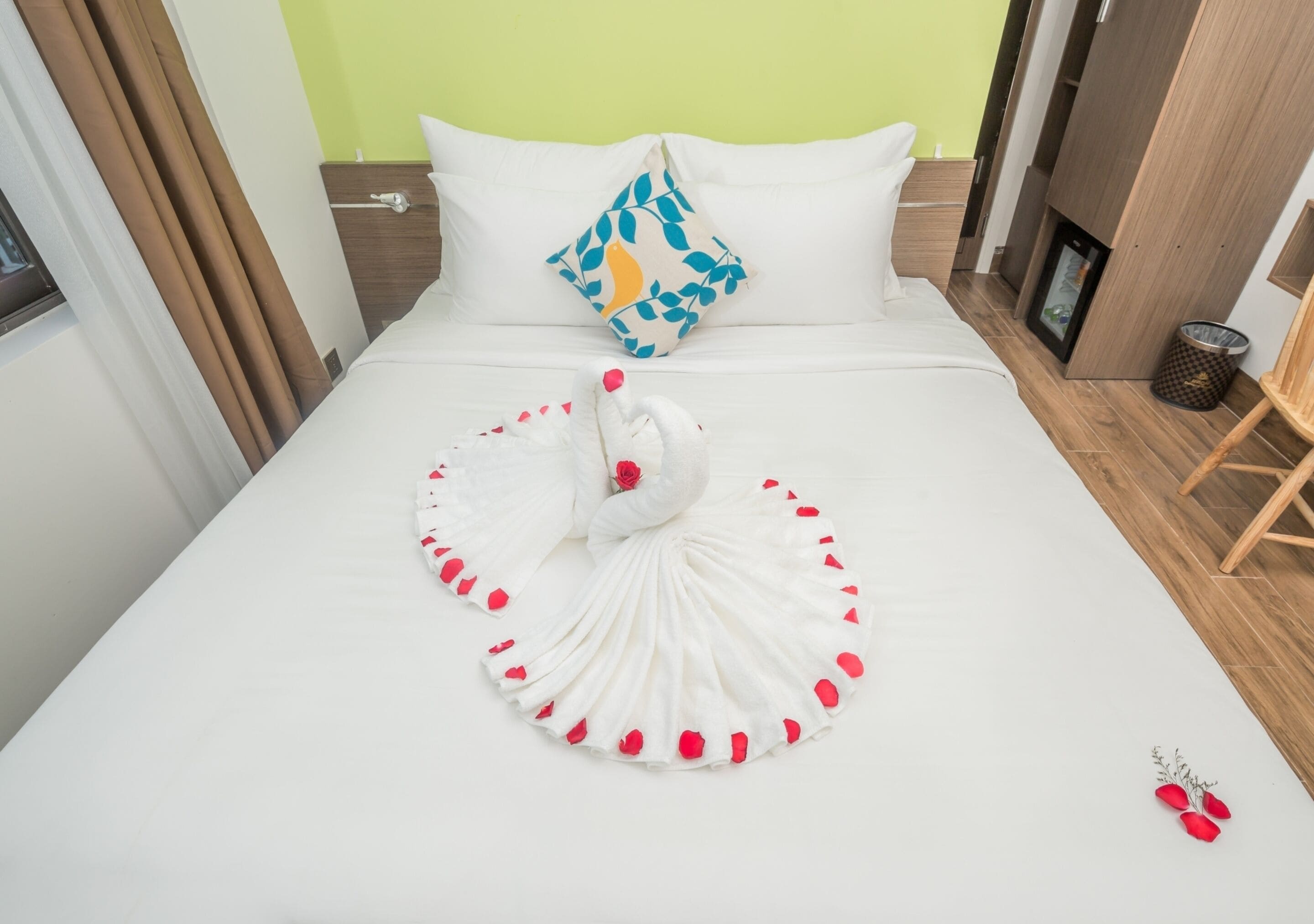A neatly made bed with a swan-shaped pillow and a swan decoration on the bed.