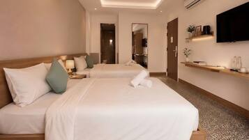 A hotel room with two beds, a TV, a shelf with items, and a mirror.