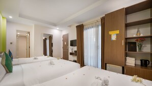 Une chambre d’hôtel avec deux lits, une armoire en bois, une télévision et une petite kitchenette.