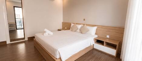 A modern hotel room with a wooden bed, a nightstand, a built-in shelf, and a large mirror.