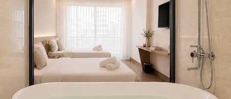 A modern bathroom with a freestanding bathtub, a shower, and a large window with sheer curtains.