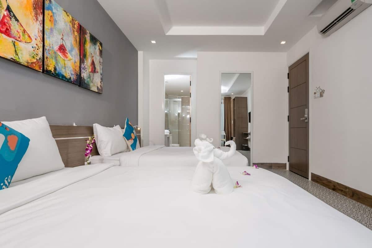 Ein Hotelzimmer mit einem großen Bett, einem Sofa, einem Bild an der Wand und einem durchgegangenen Tür erkennbaren Badezimmer.