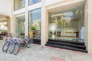 A hotel entrance with glass doors, a visible staircase, and bicycles parked outside.