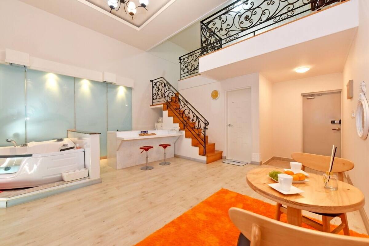Eine moderne Küche mit weißer Arbeitsplatte, einem eingebauten Ofen und einem Spülbecken. Eine Holztreppe mit schwarzer Geländer führt in eine obere Ebene.