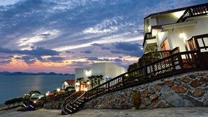 Un hotel frente al mar, con una escalera de piedra que conduce a un balcón.