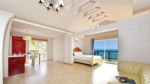 Una habitación amplia con cama, sofá, zona de comedor y vistas al mar.