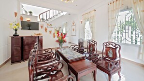 A dining area with wooden furniture, a chandelier, and a staircase. - Ly Phuc Homestay (Da Nang)