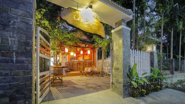 A restaurant with a stone facade, outdoor seating, and a sign above the entrance. - Ly Phuc Homestay (Da Nang)