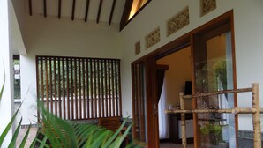 A room with a wooden bench, a bamboo stand, and a view of greenery outside. - Artati Lombok Bungalows & Restaurant (Selong Belanak)