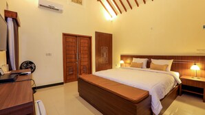 A bedroom with a wooden bed, bedside tables, a desk, and an air conditioning unit. - Artati Lombok Bungalows & Restaurant (Selong Belanak)