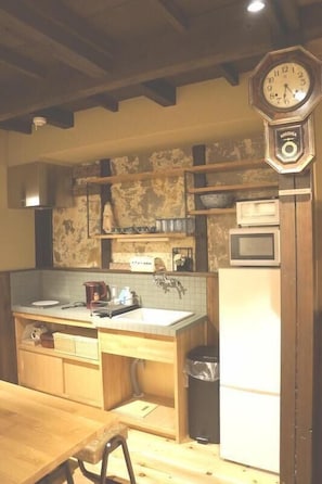 Eine Küche mit Holzausstattung, einer Holz Arbeitsplatte, einem Spülbecken, einer Mikrowelle und einer Uhr an der Wand.