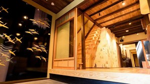 A modern interior with a wooden ceiling, large windows, and a staircase leading to an upper level. - Guesthouse Gokurakudo - Hostel (Kyoto)