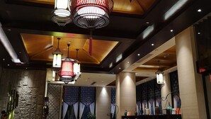 A spacious lobby with a wooden ceiling, multiple hanging pendant lights, a reception desk, a seating area with sofas, and a bookshelf filled with books. - Relaxed Season Hotel - Foshan (Foshan)