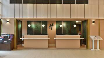 A reception area with two counters, a wall-mounted sign, and a display stand with brochures.
