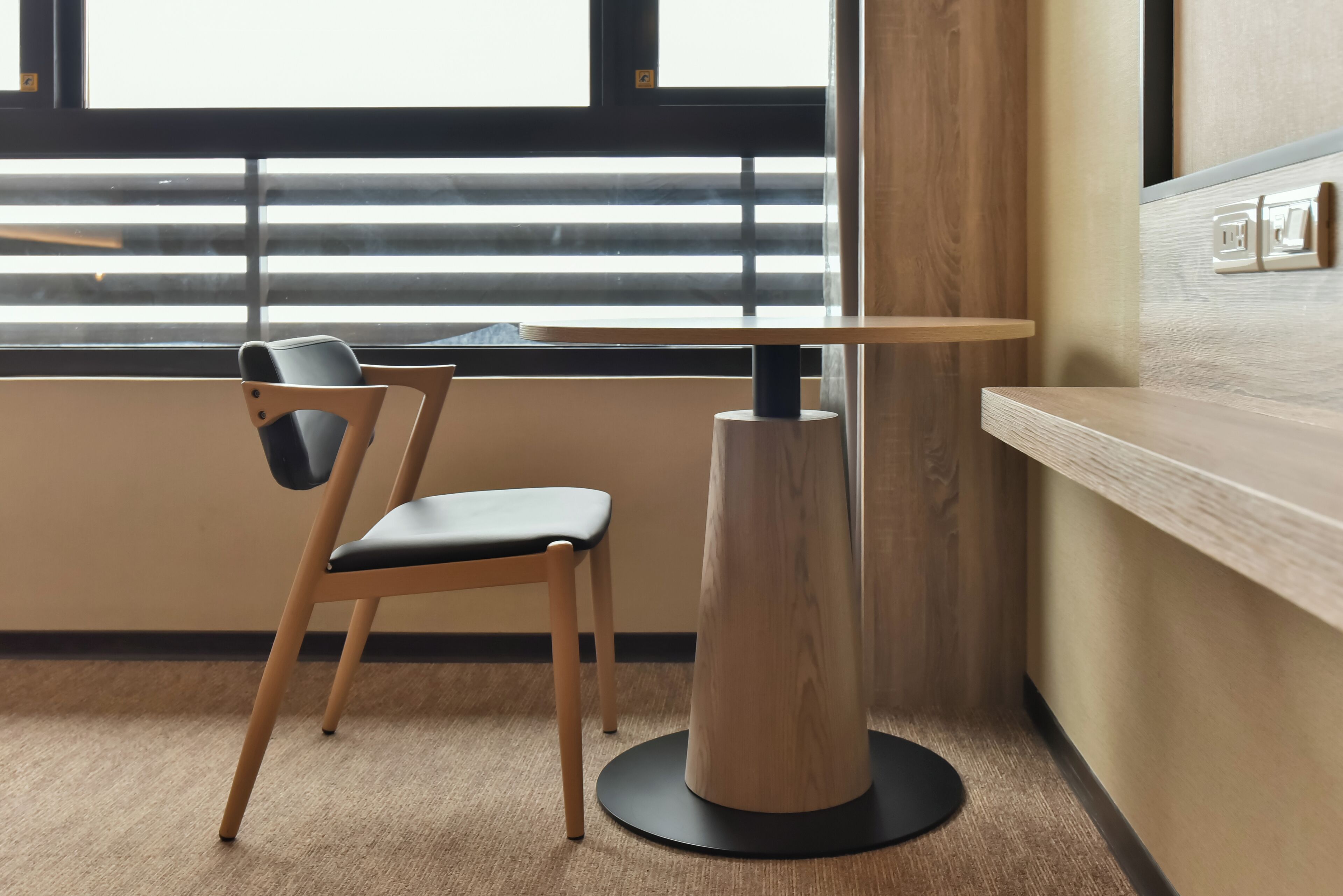 Una habitación moderna con una silla de madera y una mesa redonda.
