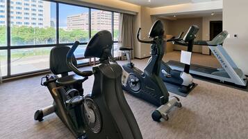 Uma academia com bicicletas ergométricas, elípticos e esteira.