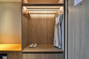 Ein begehbarer Kleiderschrank mit Holzvertäfelung, einer Sitzbank mit Schuhen und aufgehängter Kleidung.