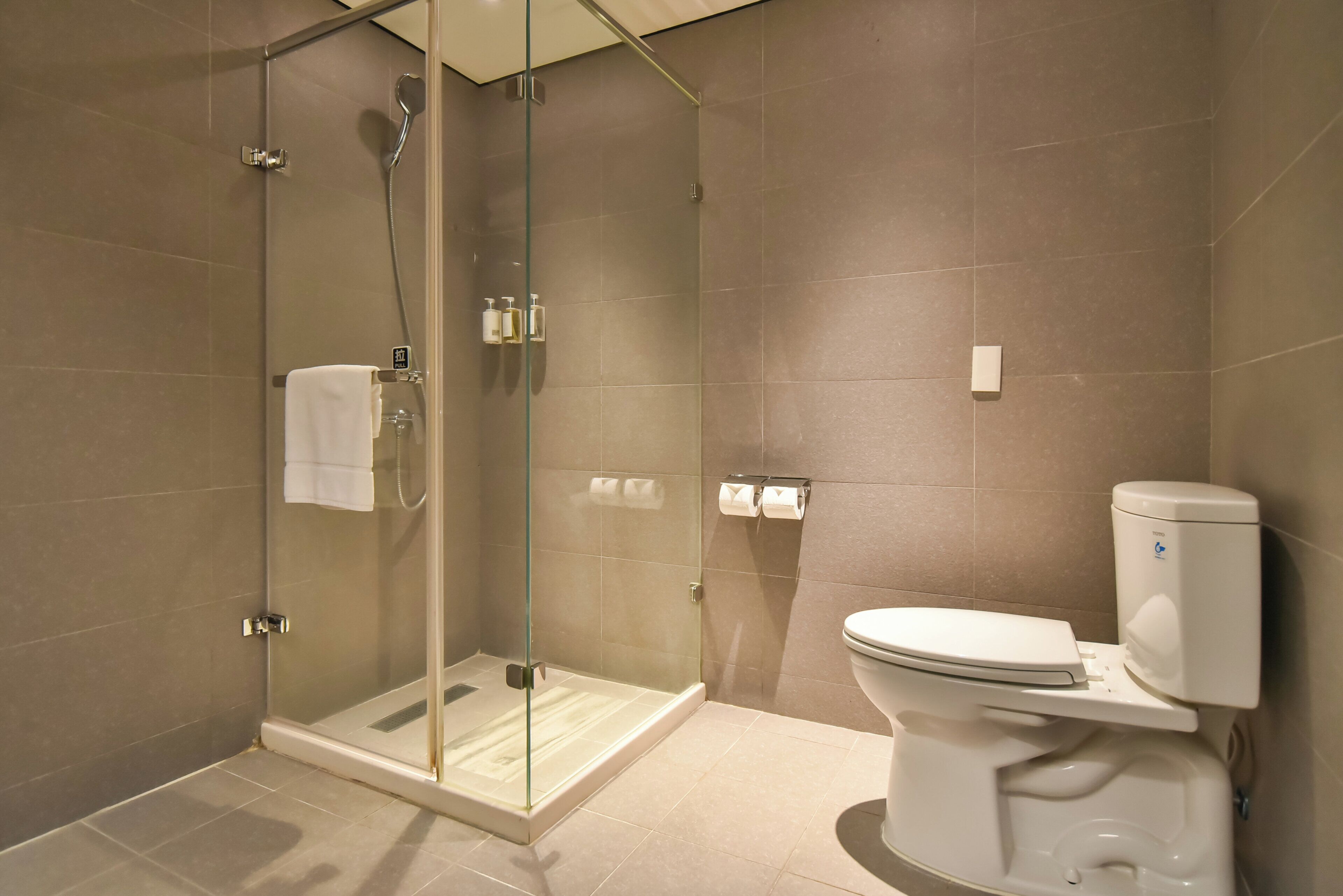 A modern bathroom with a glass-enclosed shower, a toilet, and a towel rack.