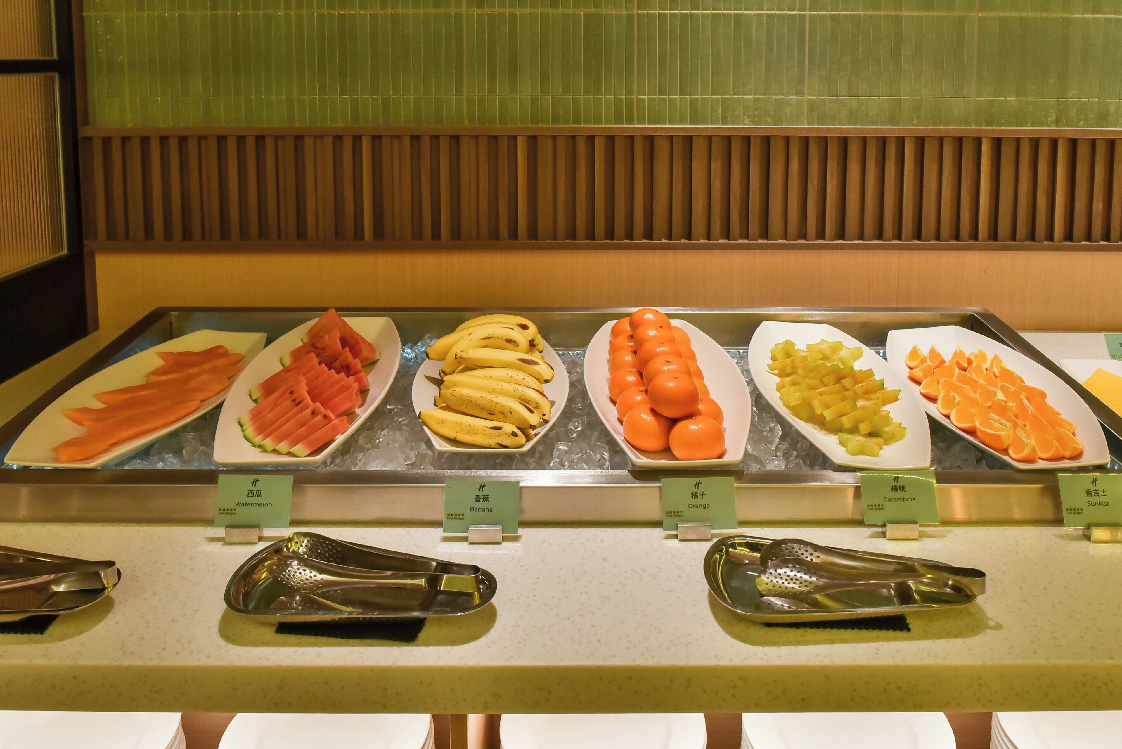 Un buffet proposant une variété de fruits et de légumes, notamment des pastèques, des bananes et des oranges.