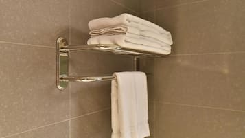 Un bagno con un portasciugamani pieno di asciugamani piegati e un asciugamano singolo appeso.