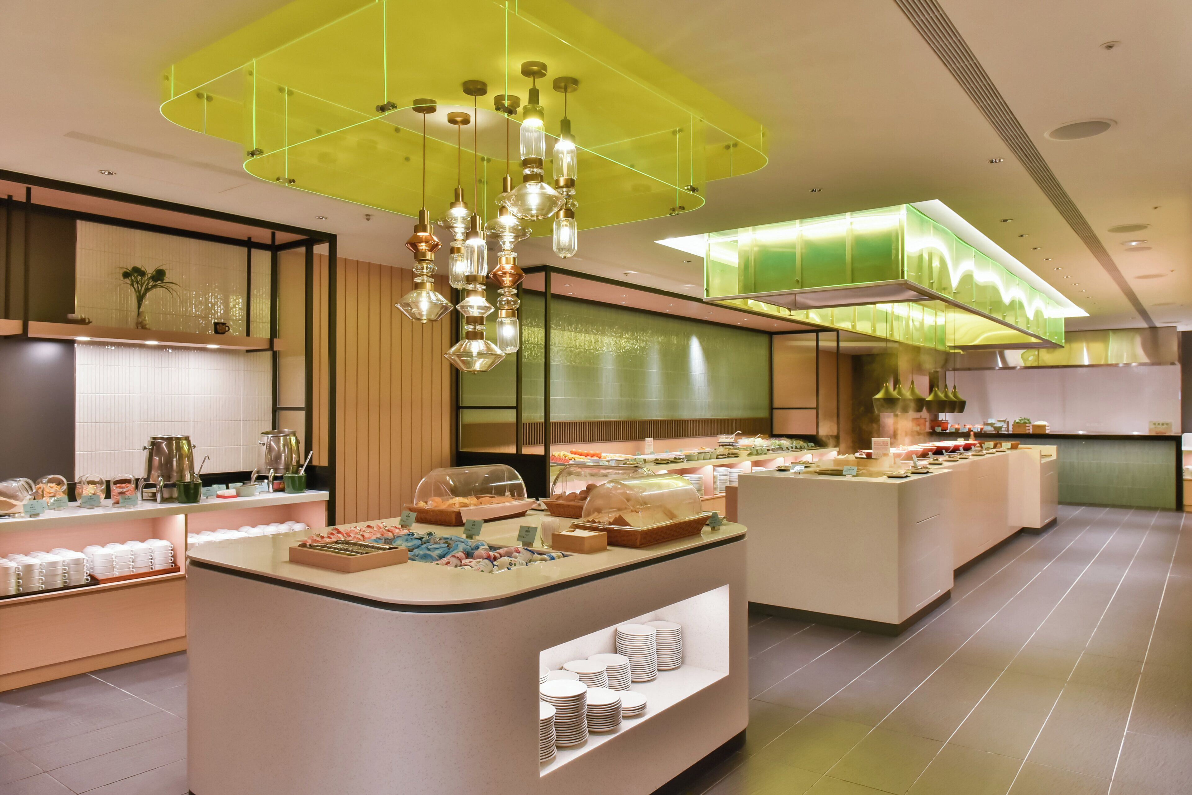 A modern breakfast area with a central serving station, glass display cases, and ambient lighting.