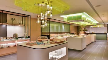 A modern breakfast area with a central serving station, glass display cases, and ambient lighting.