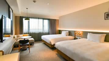 A hotel room with two beds, a desk, a chair, and a large window with curtains.