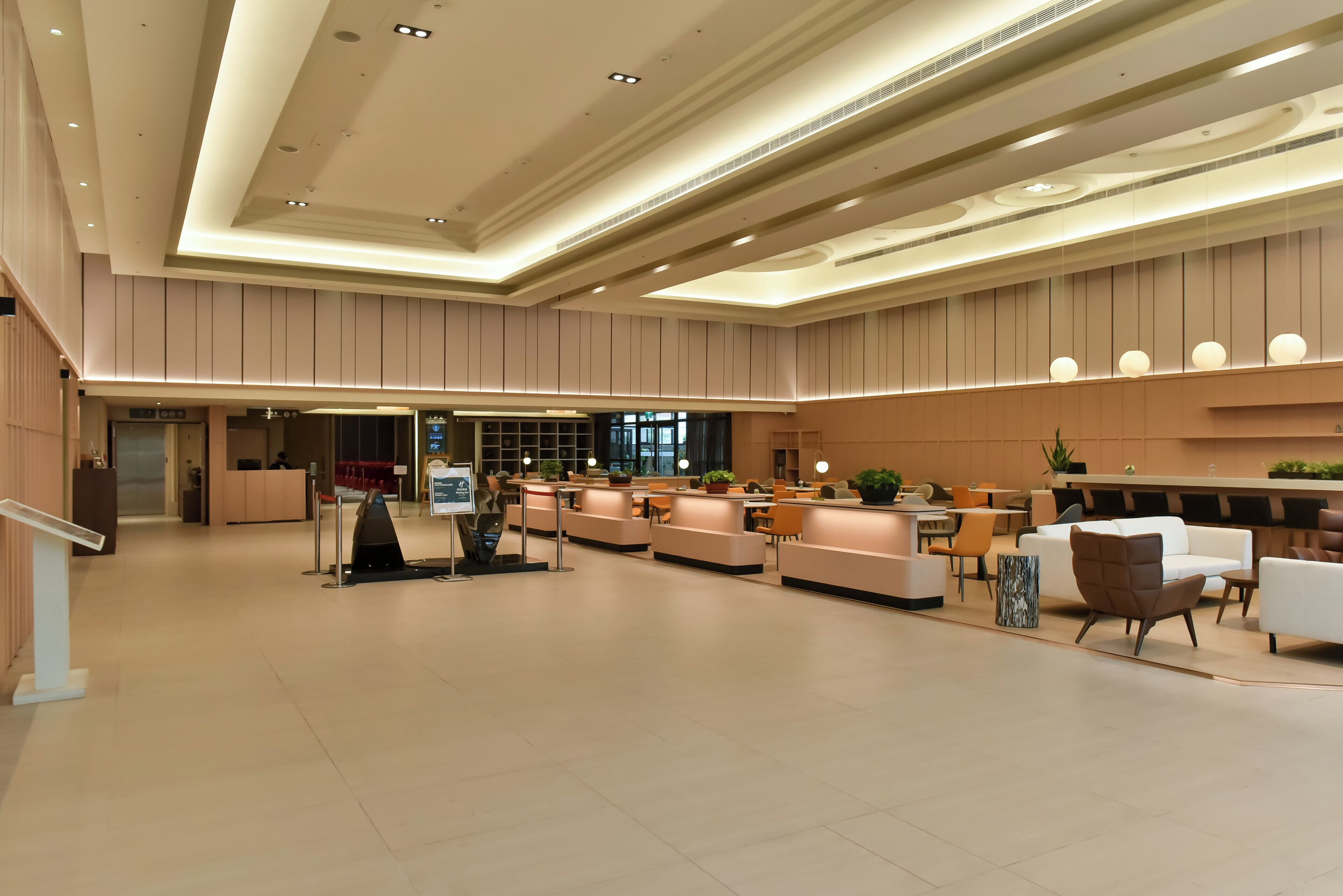 A spacious lobby with a reception desk, seating areas, and a modern ceiling design.