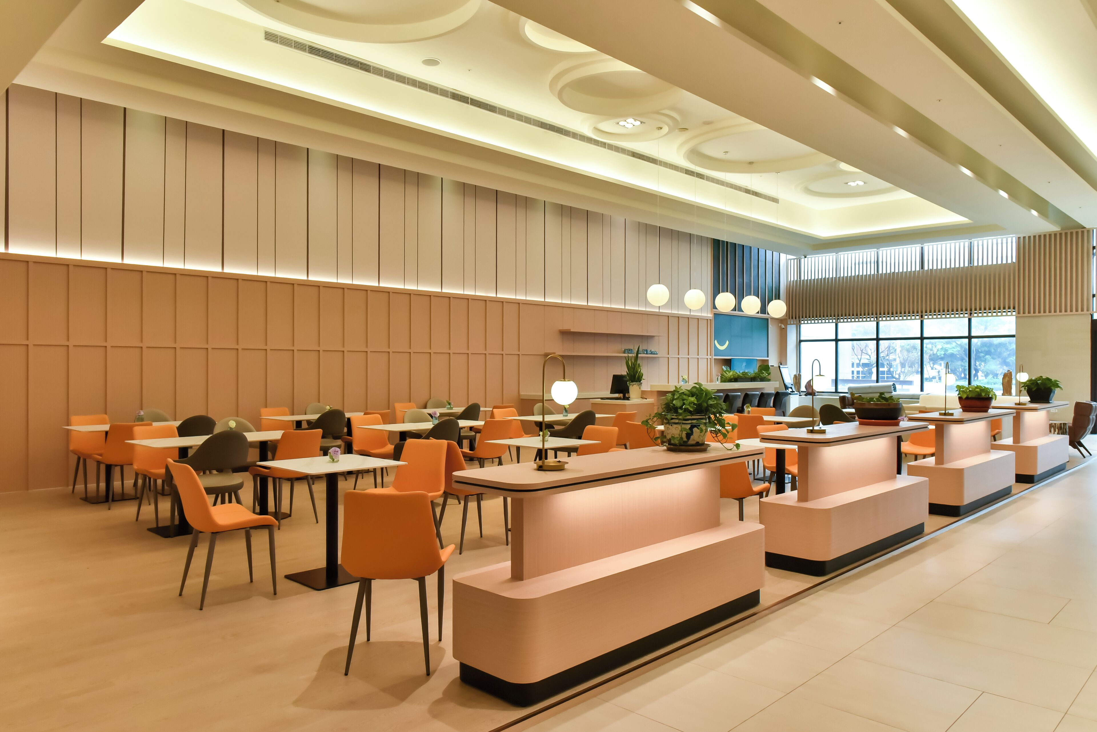 Un restaurante moderno con una barra alargada, sillas anaranjadas y una zona de estar central.