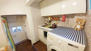 A compact kitchen with a washing machine, a small sink, and a bear decoration. - FILL HOUSE (Seoul)