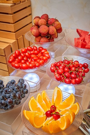 Diversas frutas expuestas en recipientes de vidrio transparente sobre una mesa.