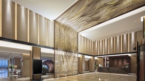 Eine großzügige Lobby mit modernem Design, inklusive einer Rezeption, einer Sitzecke und einer großen Wanddekoration.