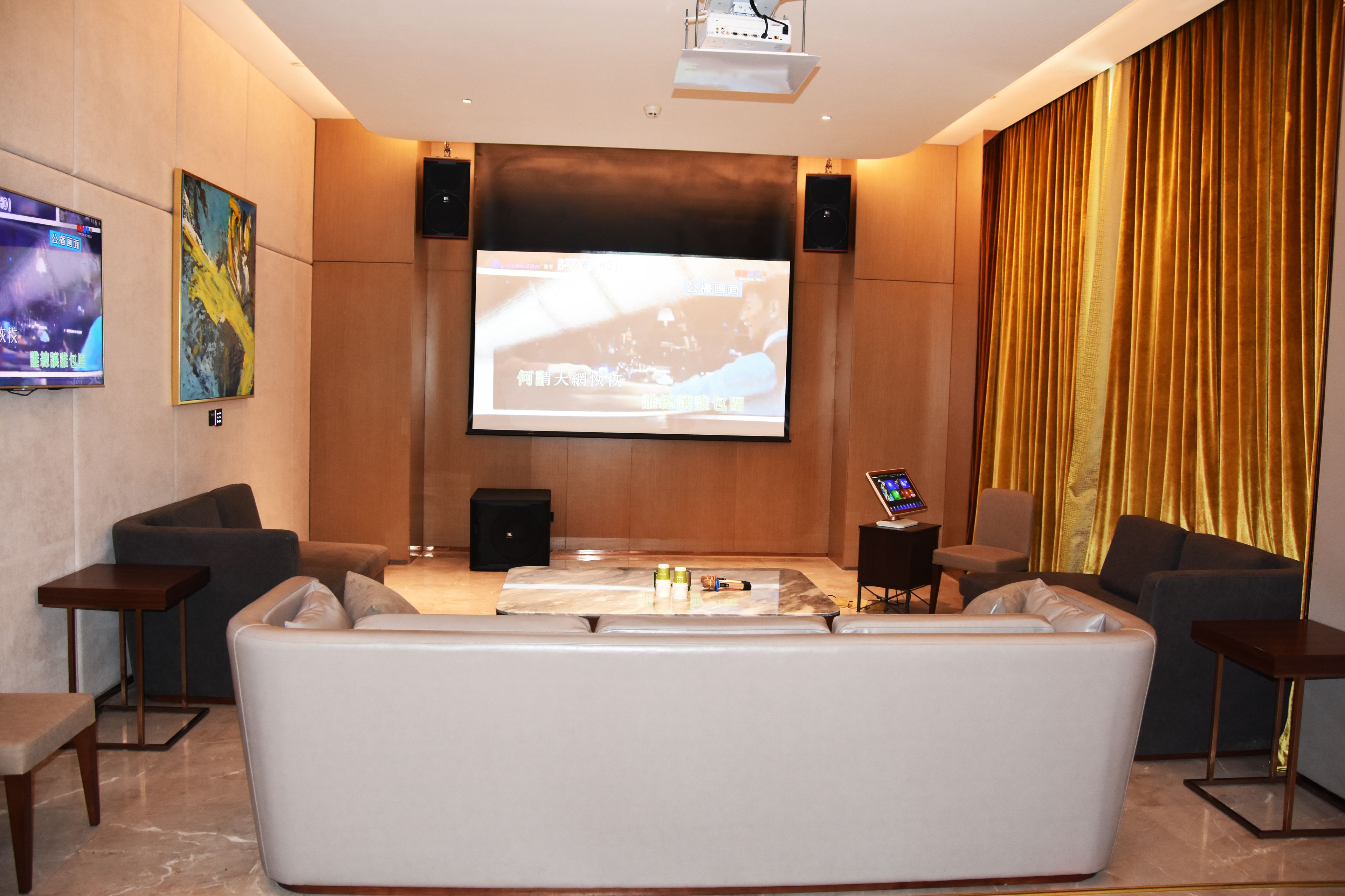 Un área de lounge moderna con una pantalla grande, asientos cómodos y un proyector.