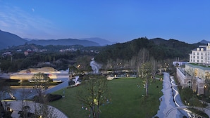 Ein Hotel mit einem großzügigen, gut beleuchteten Gebäude, einem weitläufigen Innenhof mit Brunnen und Blick auf die umliegenden Hügel.