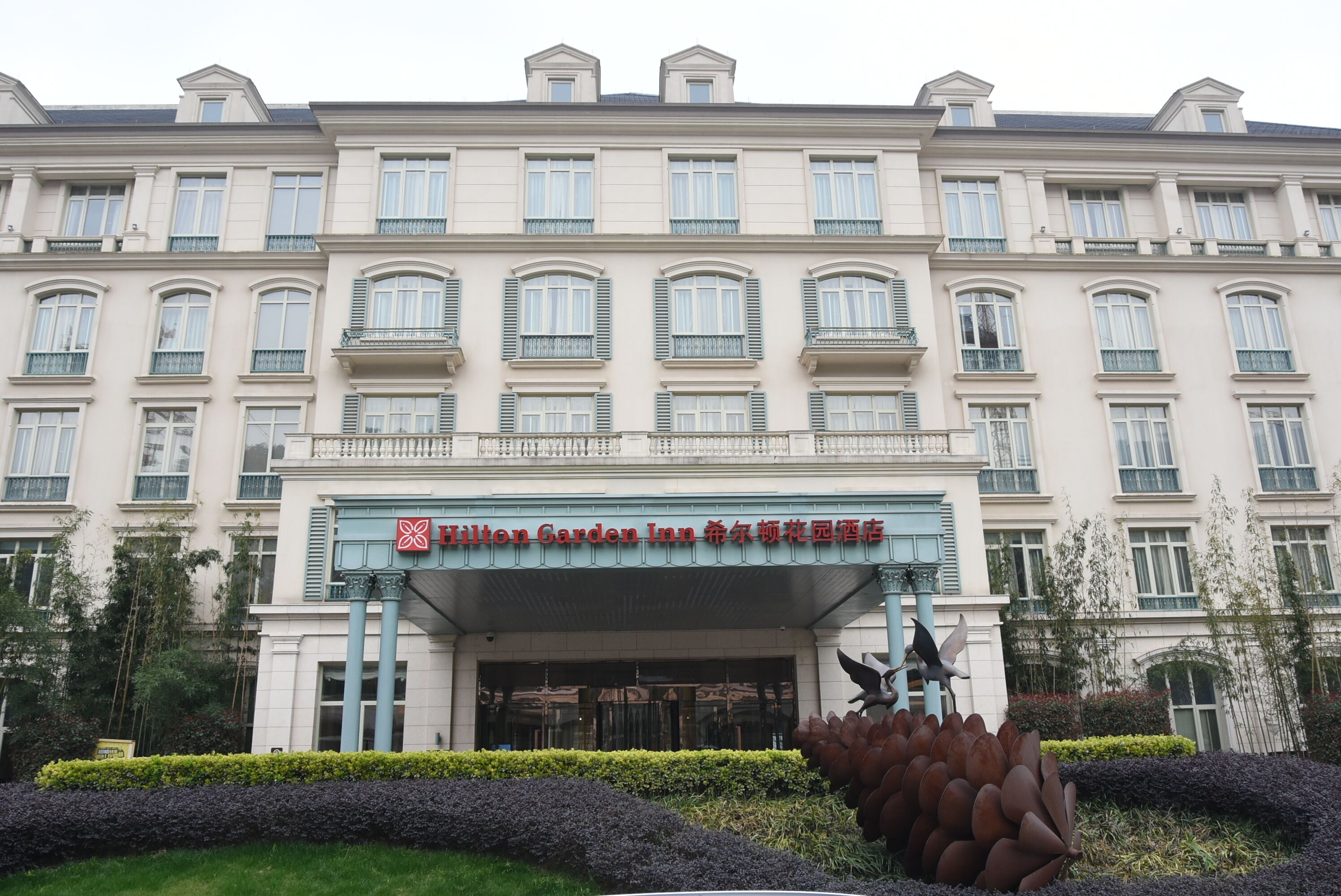 A large, multi-story building with a prominent entrance featuring a sign for Hilton Garden Inn.