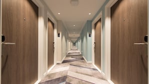 Un pasillo de hotel con pisos alfombrados, puertas de madera y una lámpara en el techo.