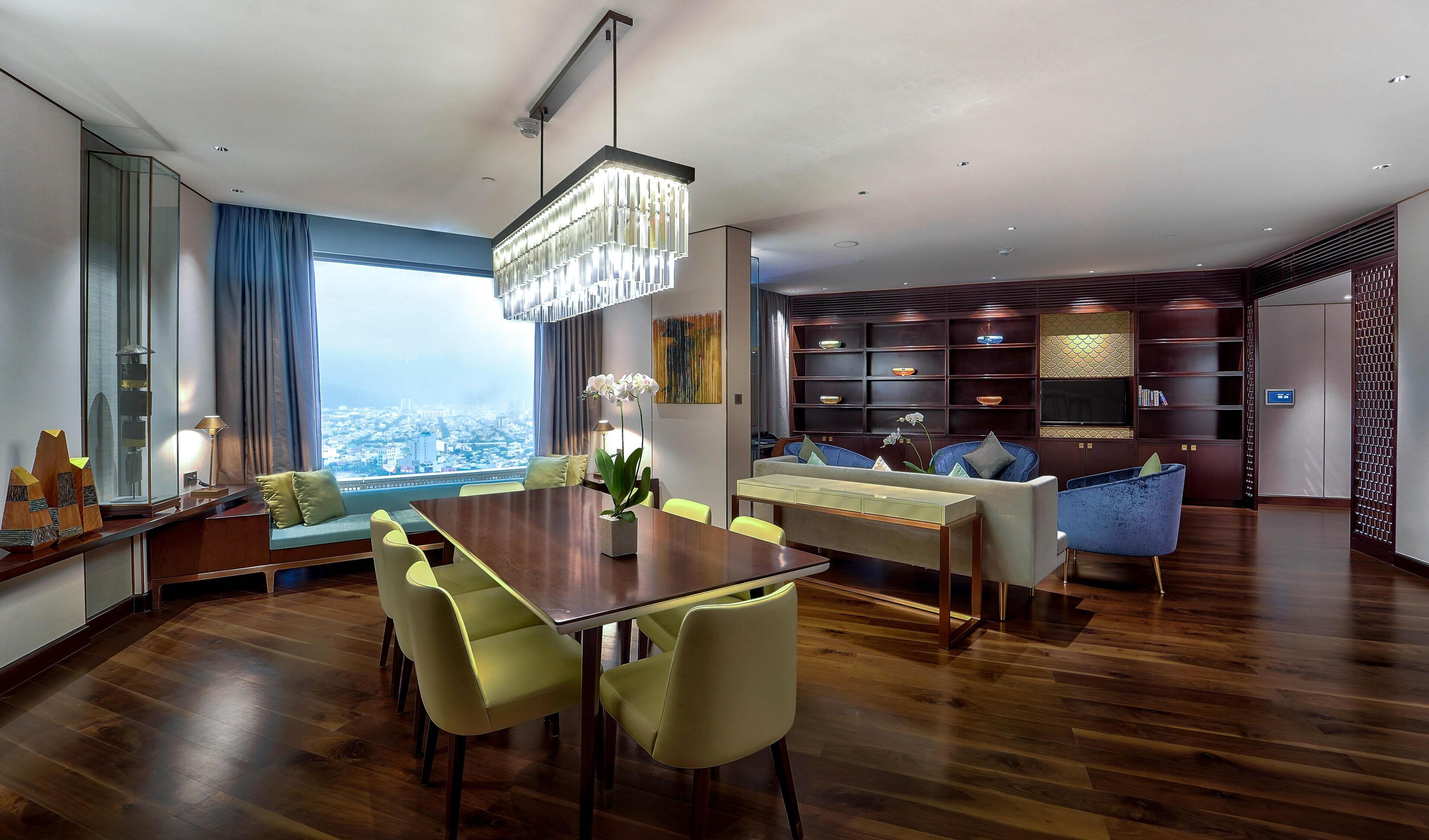A modern living room with a dining area, large windows, and a city view.