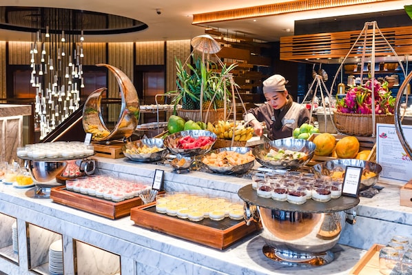 A buffet with various food items and a chef preparing food. - Hilton Da Nang (Da Nang)