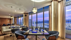 Un comedor moderno con vista a la ciudad, una mesa larga con sillas y una zona de bar al fondo.