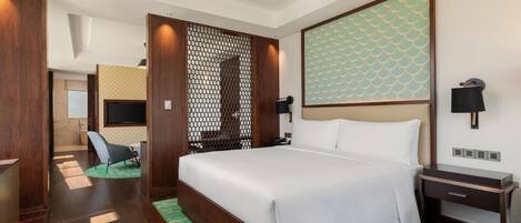 Una habitación de hotel con una cama grande, un escritorio, una silla, un televisor y un panel decorativo en la pared.