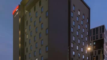 Een modern hotel met een opvallend 'Hampton'-bord, meerdere verdiepingen en een goed verlichte gevel.